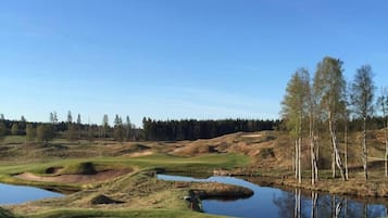 A golf course with bunkers, water hazards, and a clear blue sky.