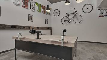 A modern room with a long table, wall-mounted bicycles, and sports jerseys.