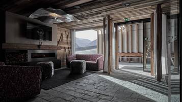 A rustic interior with a fireplace, seating area, and a view of mountains.