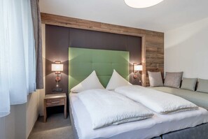 Ein Hotelzimmer mit einem großen Bett, zwei Nachttischen, einem grünen Kopfteil und zwei Wandlampen.