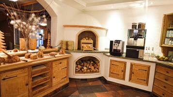 A cozy kitchen with wooden cabinets, a built-in wood stove, and a coffee machine.