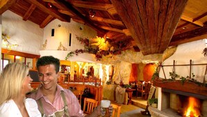 Un interior rústico con chimenea de piedra, vigas de madera y una zona de bar.