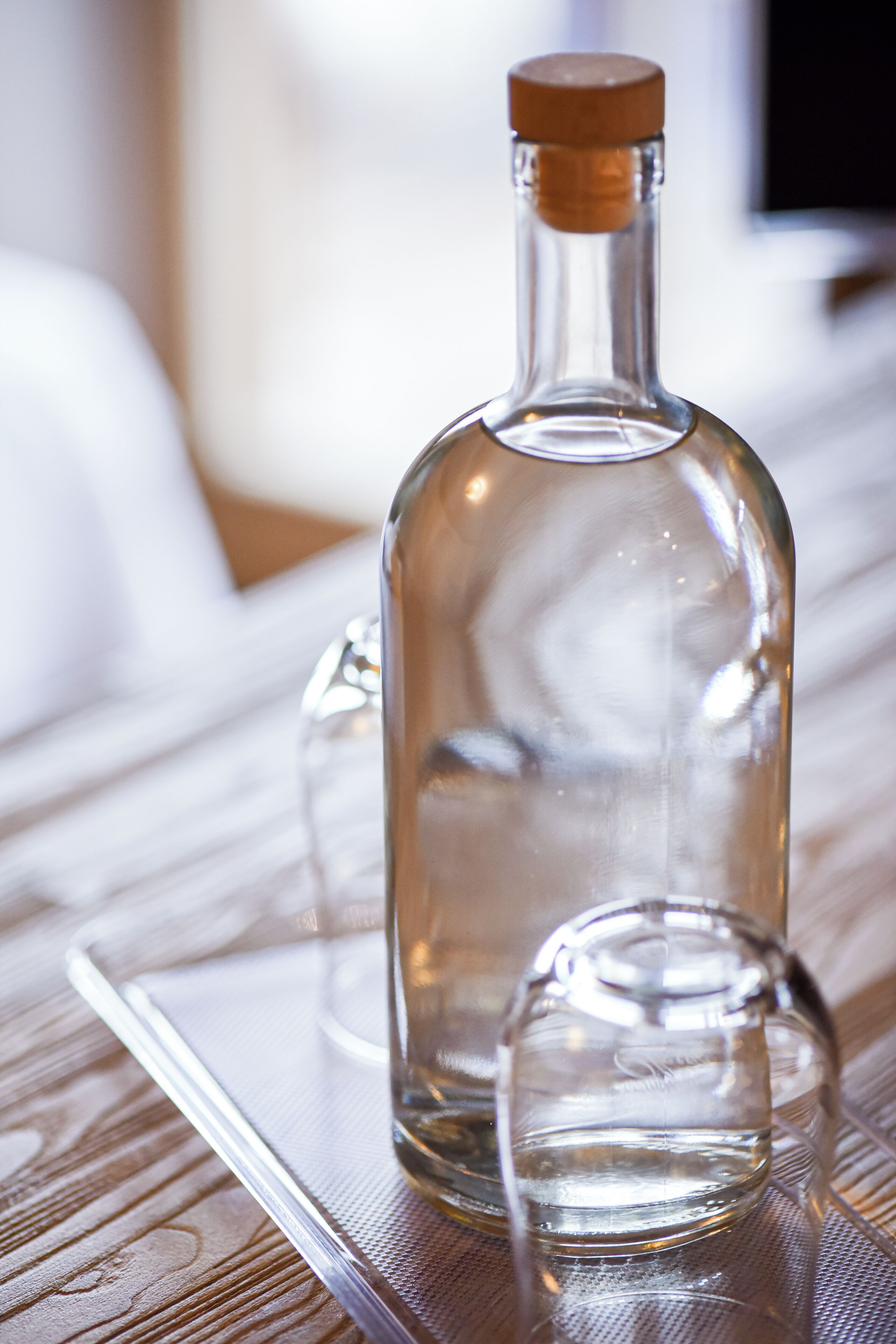 Une bouteille en verre transparent, fermée par un bouchon en liège, posée sur une surface texturée.