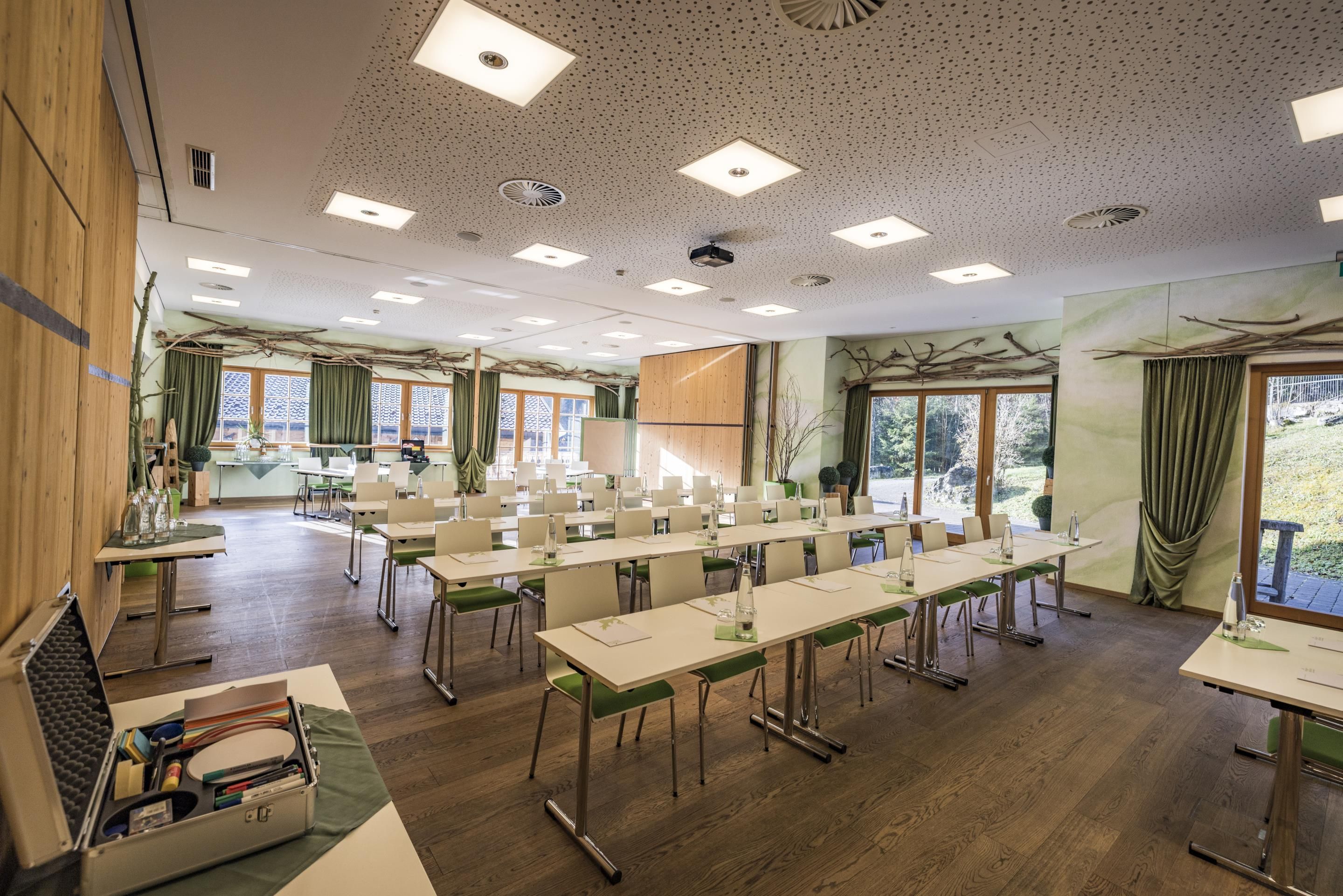 A conference room with long tables, chairs, and a projector screen.