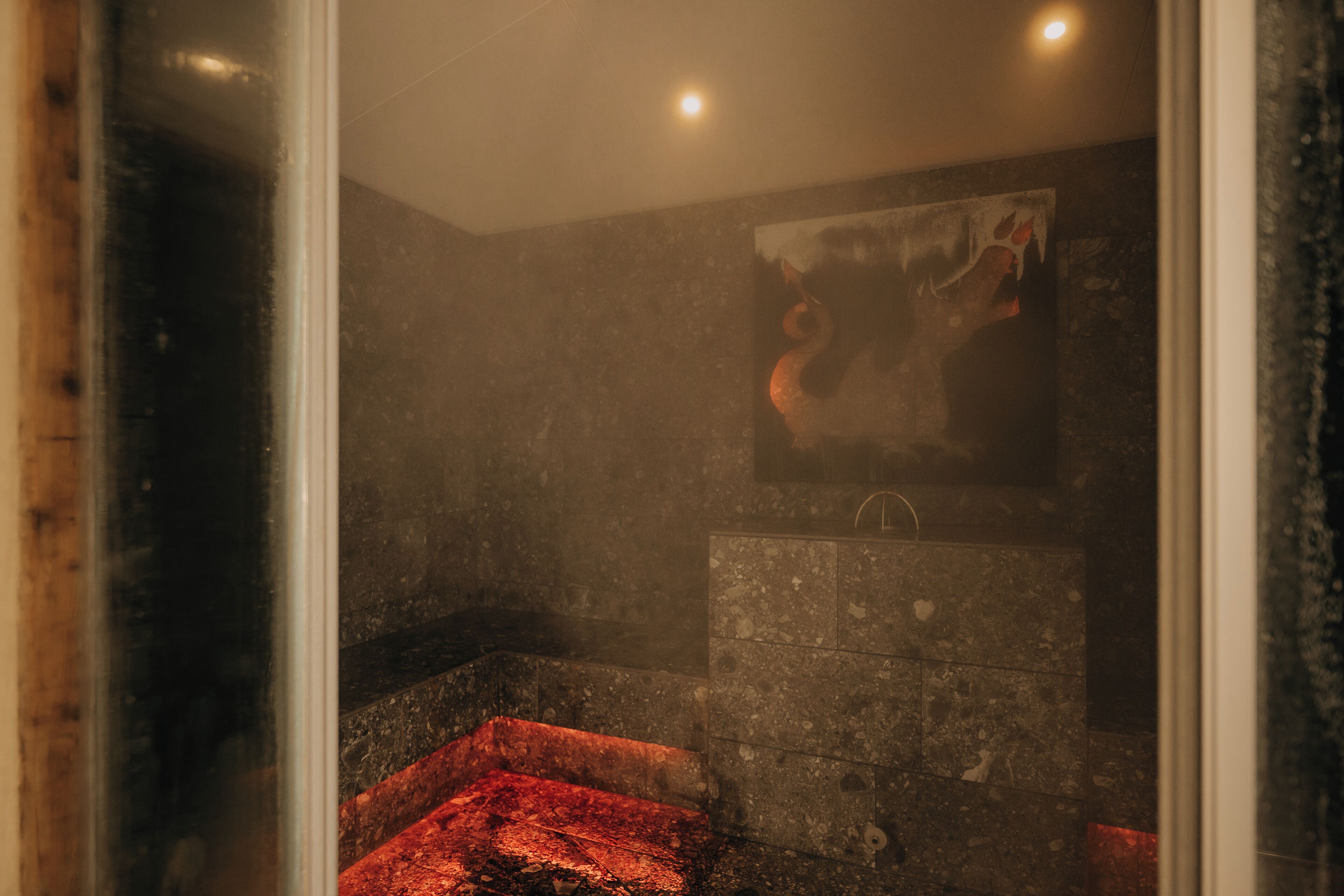 A steam room with a stone bench and a painting on the wall.