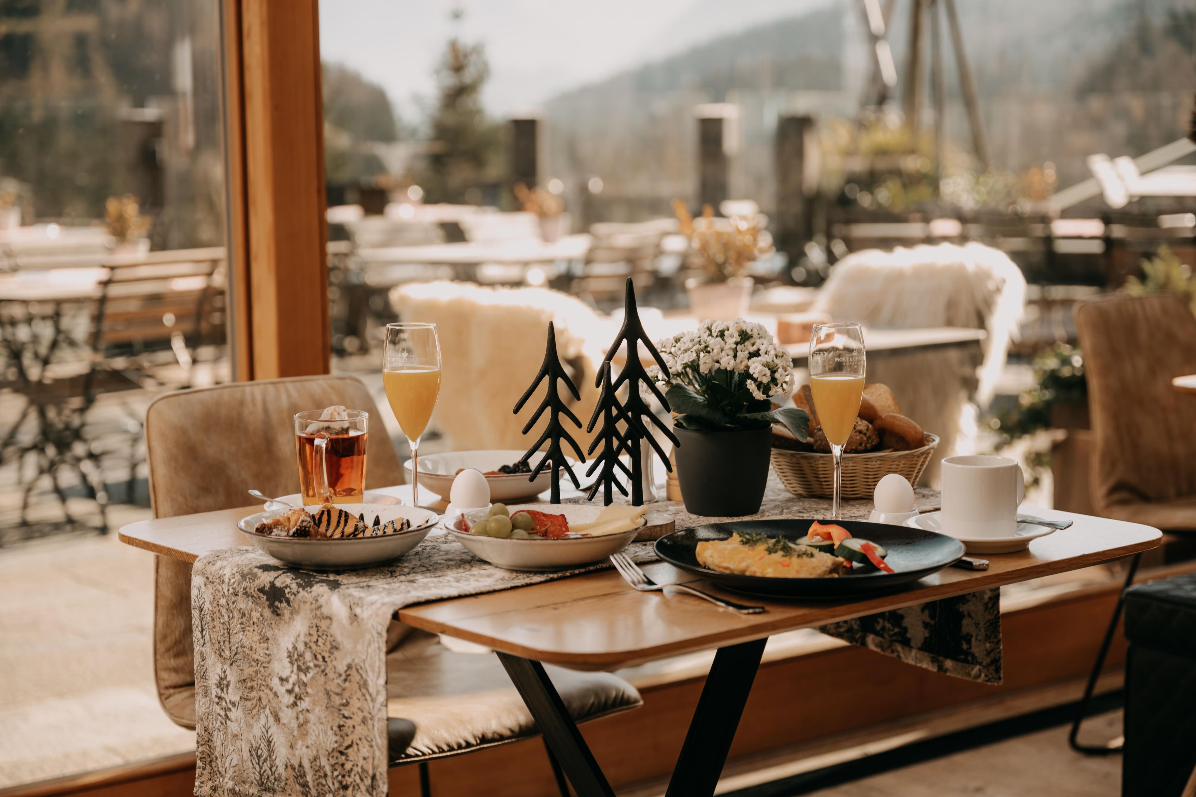 A dining table set with plates of food, glasses of beverages, and a decorative tree.