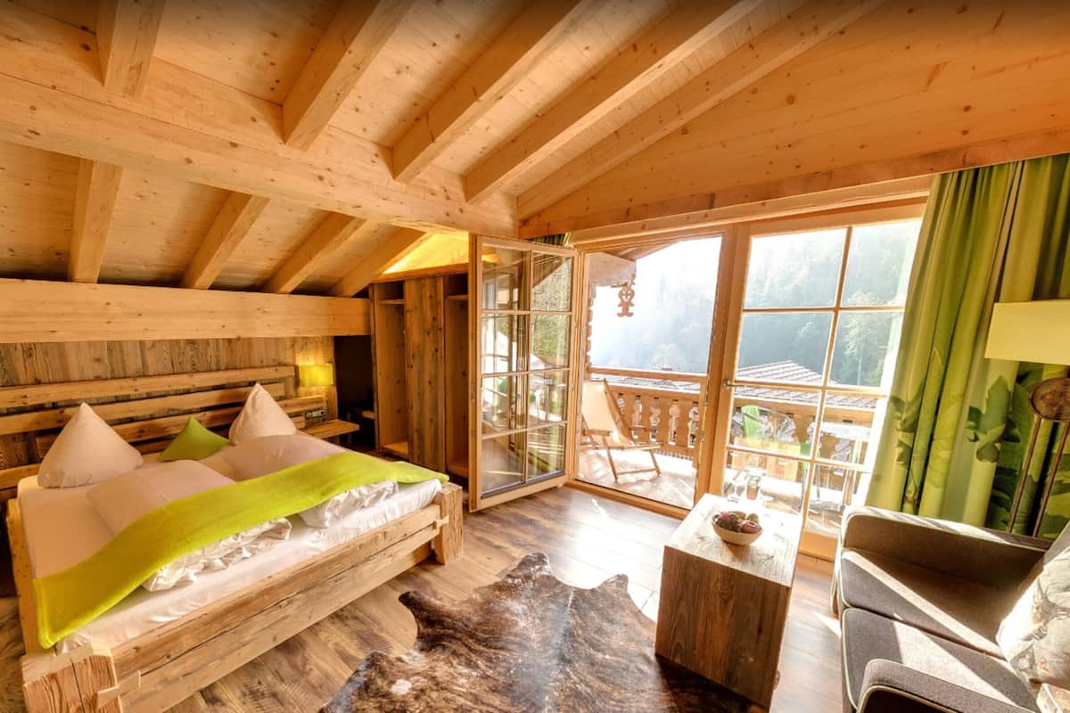 Un dormitorio tipo cabaña de madera con una cama, un sofá, una mesita y vistas al exterior.