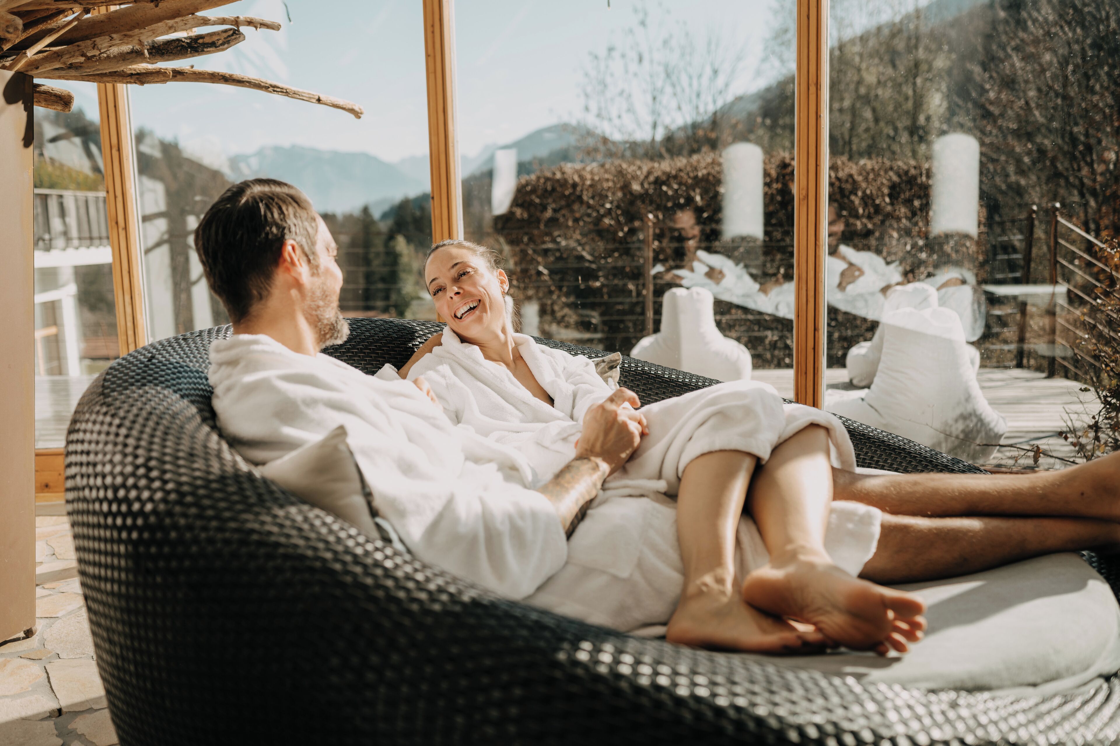 A couple relaxing on a wicker lounge chair with a view of the mountains.