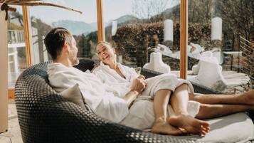 A couple relaxing on a wicker lounge chair with a view of the mountains.