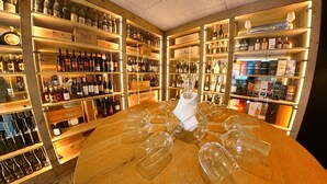 Un bar con estanterías llenas de botellas y copas, y una mesa redonda con copas de vino vacías.