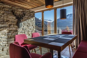 A dining area with a stone wall, a mounted deer head, and a table with red chairs. - Hunting Chalet - The Peak Sölden (Sölden)