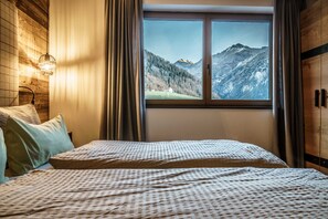 A bedroom with a large window, wooden walls, and a bed with patterned bedding. - Hunting Chalet - The Peak Sölden (Sölden)