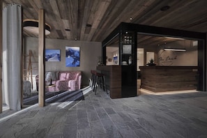 A modern interior with a stone floor, a wooden reception desk, and a bar area. - Hunting Chalet - The Peak Sölden (Sölden)