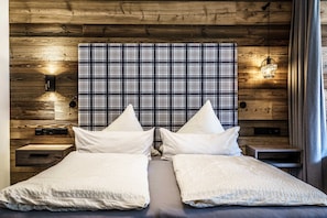 A double bed with a plaid headboard, bedside tables, and a wall-mounted light fixture.