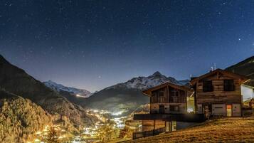 A mountain village at night with illuminated buildings and a starry sky.