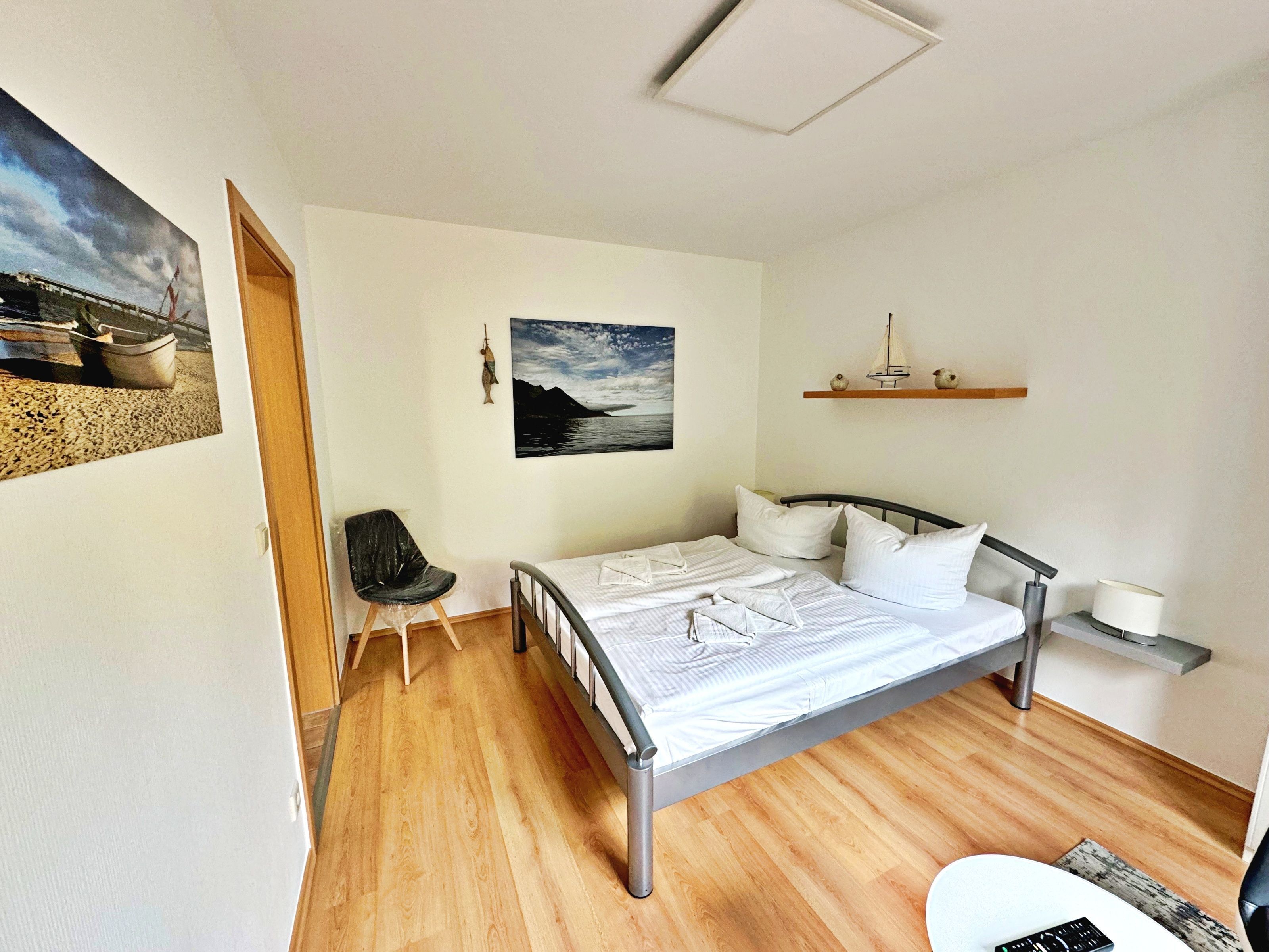 Une chambre à coucher comprenant un lit, une chaise, une étagère avec des objets décoratifs et un tableau au mur.