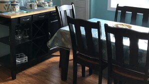 A dining area with a table set for two, a mirror above the table, and a window with blinds.