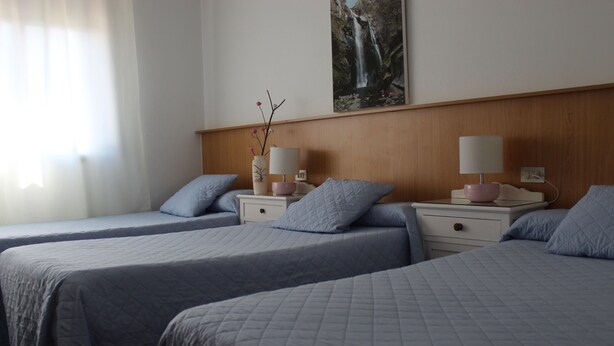 Une chambre d’hôtel avec deux lits, chacun agrémenté d’un oreiller assorti et d’une table de chevet avec une lampe et un vase.