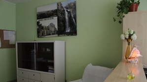 Une pièce avec un meuble blanc, un bureau en bois, une chaise blanche et un tableau accroché au mur.