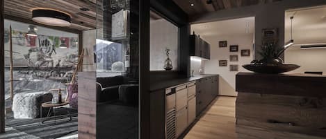 A modern kitchen with wooden cabinetry, a built-in oven, and a large window overlooking a snowy landscape.