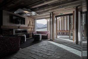 Un intérieur rustique avec une cheminée, un coin salon et une vue sur les montagnes.