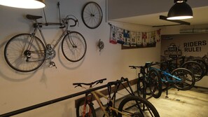 A bike storage area with multiple bicycles, a wall-mounted bike rack, and a banner with cycling-related text. - Bergsteiger Chalet - The Peak Sölden (Sölden)