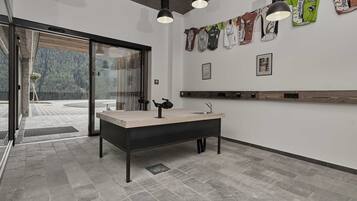 A modern bathroom with a large sink, pendant lights, and a view of a forest through glass doors.