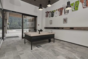 Un baño moderno con un lavamanos grande, luces colgantes y vistas a un bosque a través de puertas de vidrio.