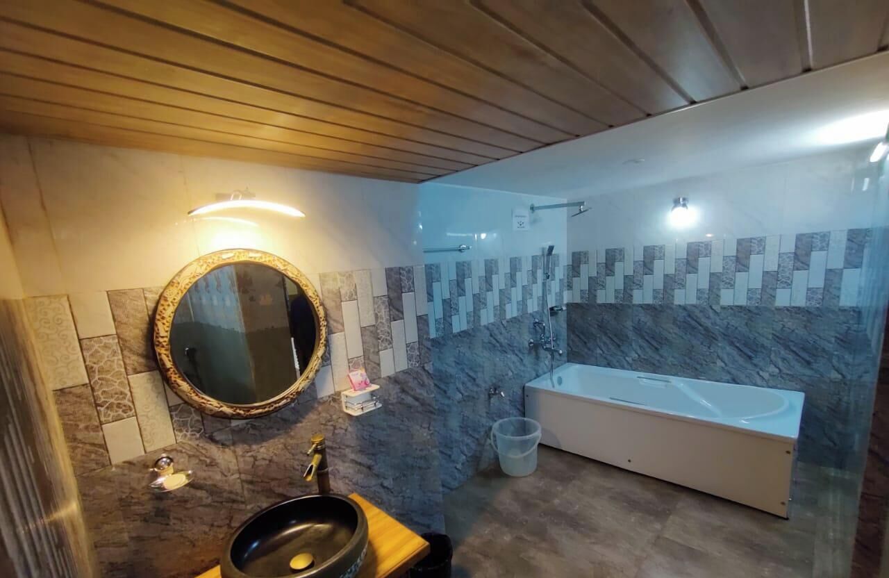 Un baño con un espejo redondo, un lavabo, una bañera y una zona de ducha.