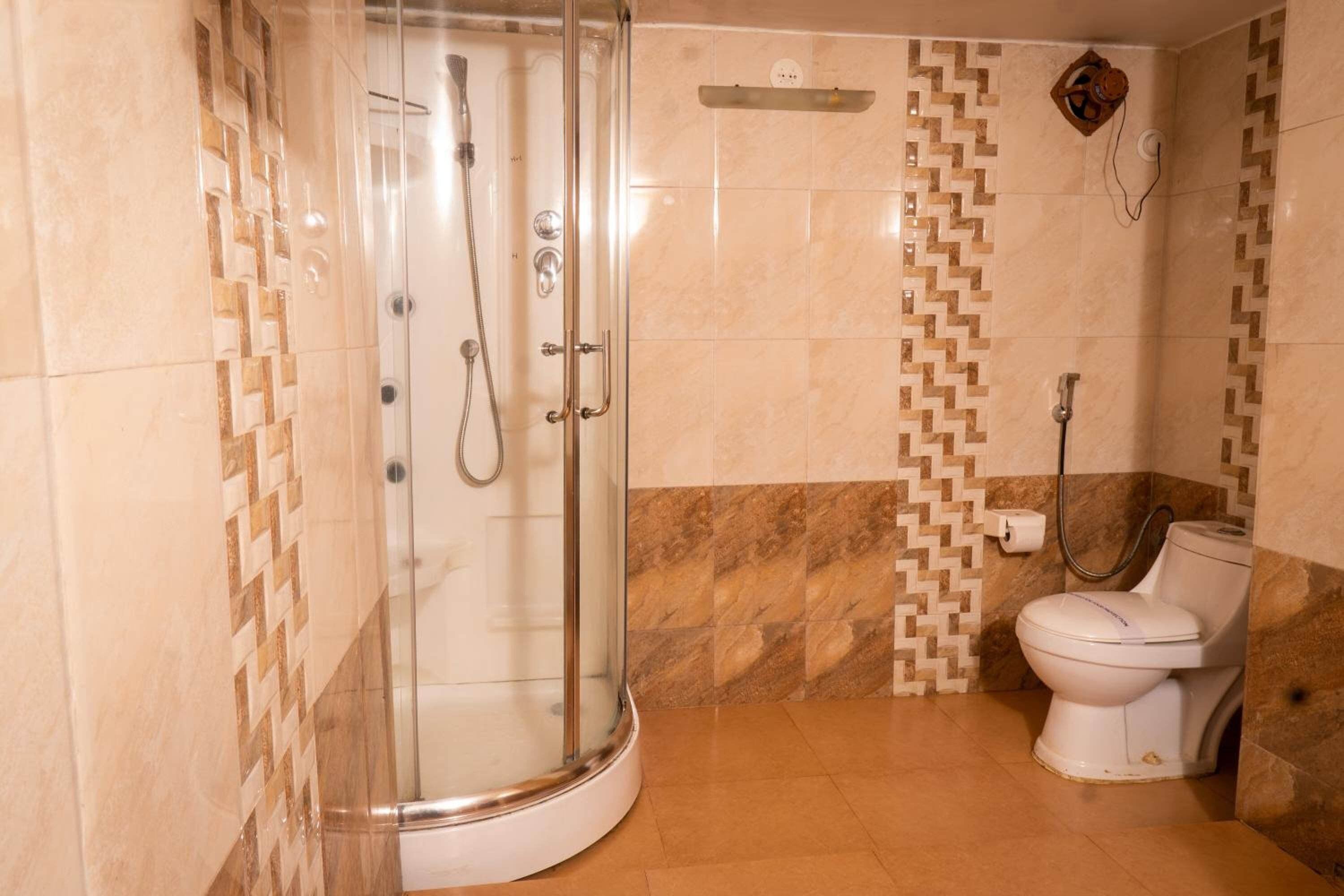 Une salle de bain avec une douche à parois de verre, des toilettes et un sol carrelé.