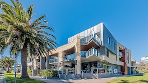 Un edificio moderno con un diseño arquitectónico singular, que cuenta con una escalera destacada y una cafetería en la planta baja.