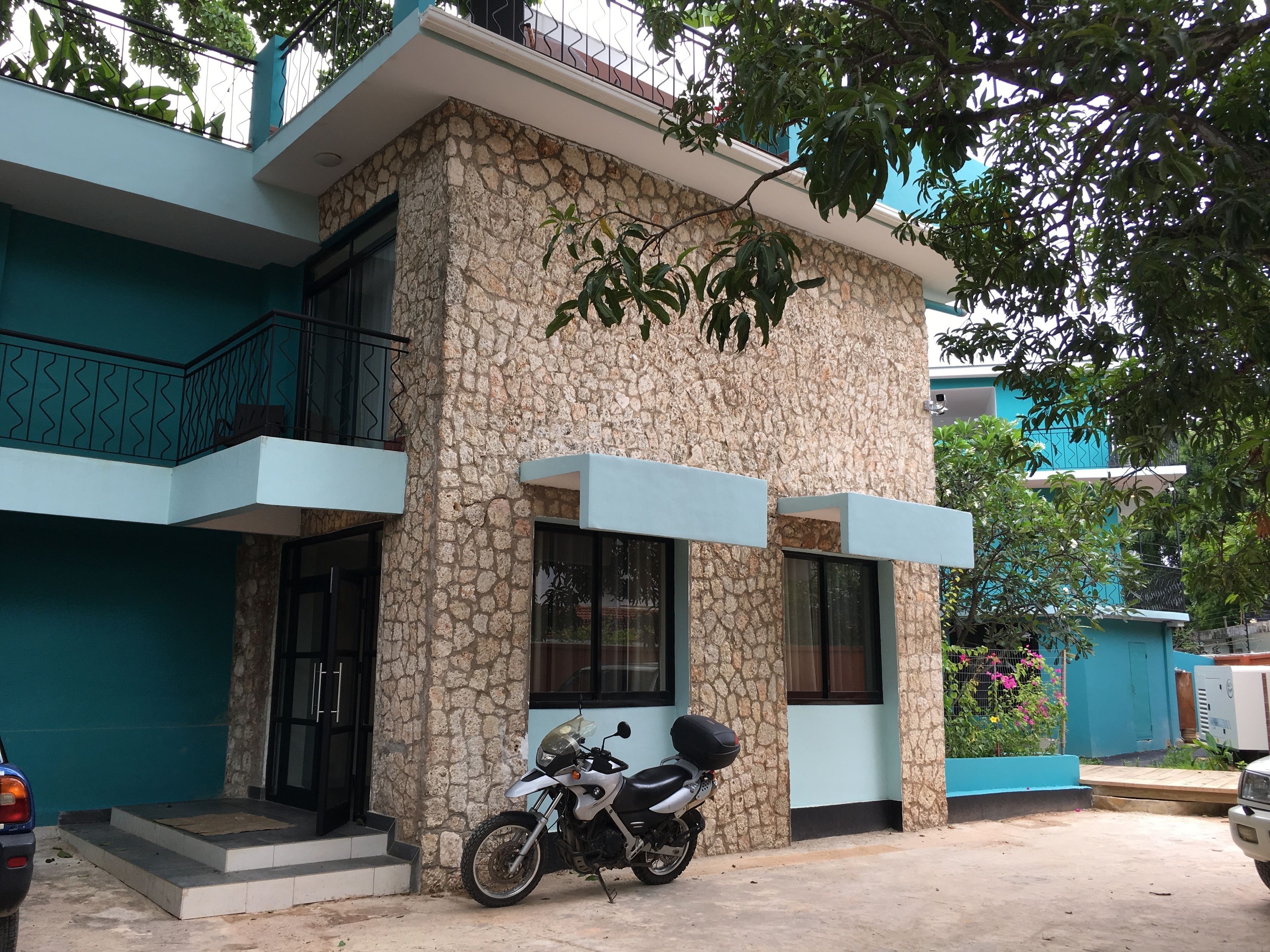 A two-story building with a stone facade, a balcony, and a parked motorcycle.