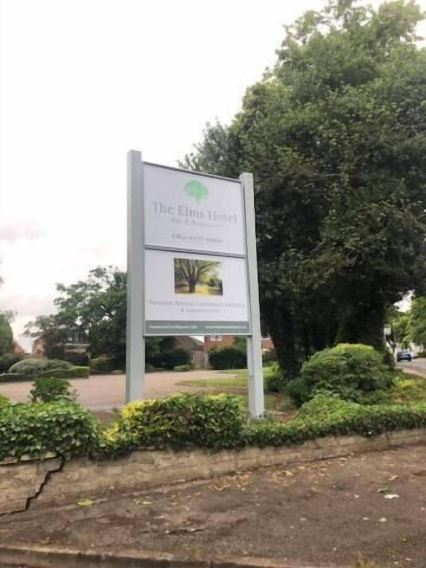En skylt för hotellet The Elm, med en logotyp och en liten bild av ett träd.