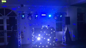 Een ruimte met een podium, inclusief een discobal en LED-verlichting.