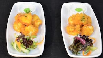 Dos platos blancos cuadrados con comida frita, cada uno acompañado de una salsera pequeña y una ensalada.