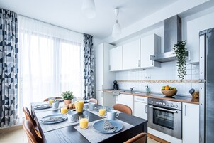 A modern kitchen with a dining table set for breakfast, a coffee maker, and a fruit bowl.