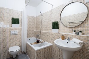 A bathroom with a toilet, a bathtub, a sink, and a mirror.