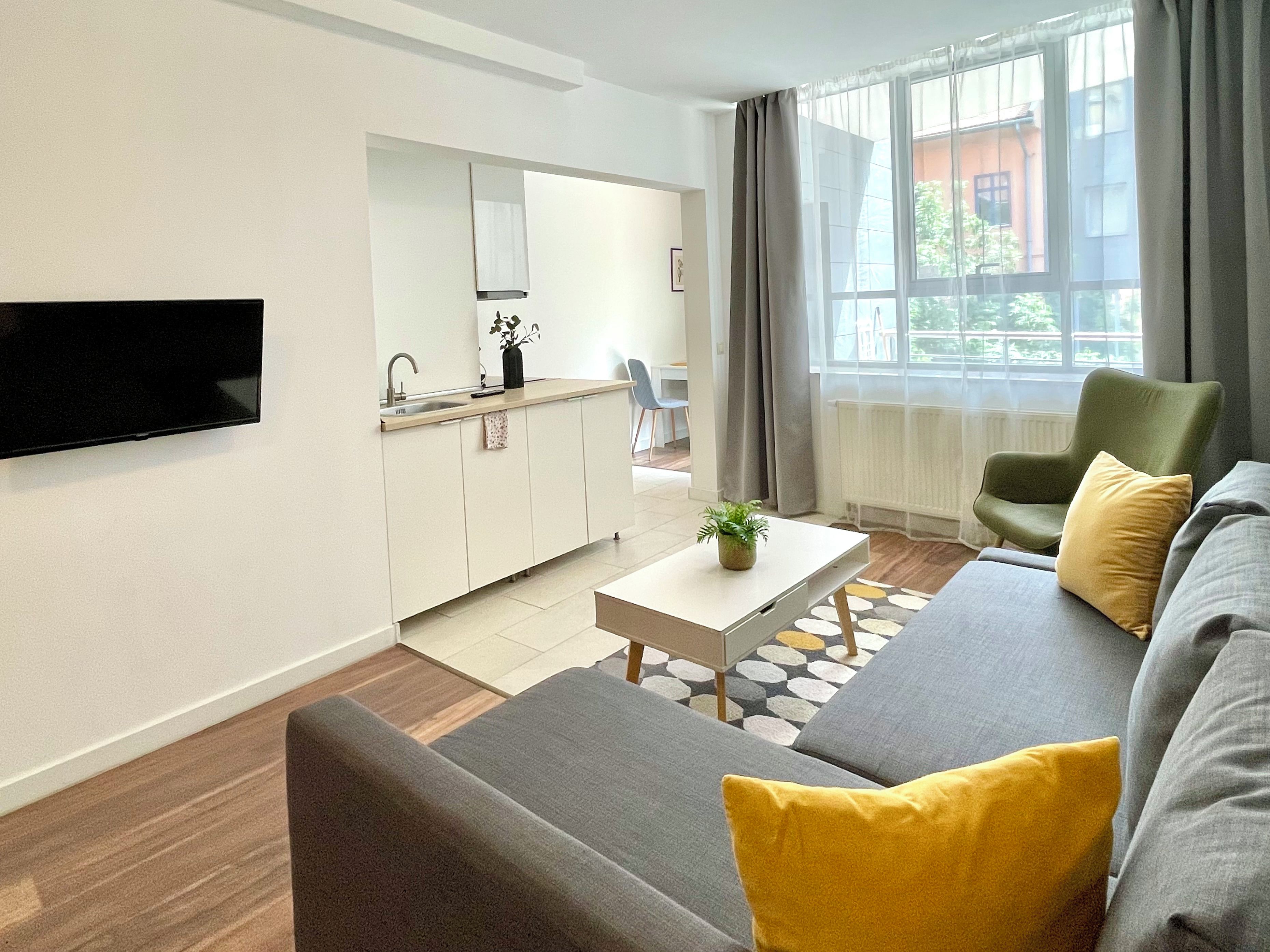 A modern living room with a sofa, a coffee table, and a flat-screen TV mounted on the wall.