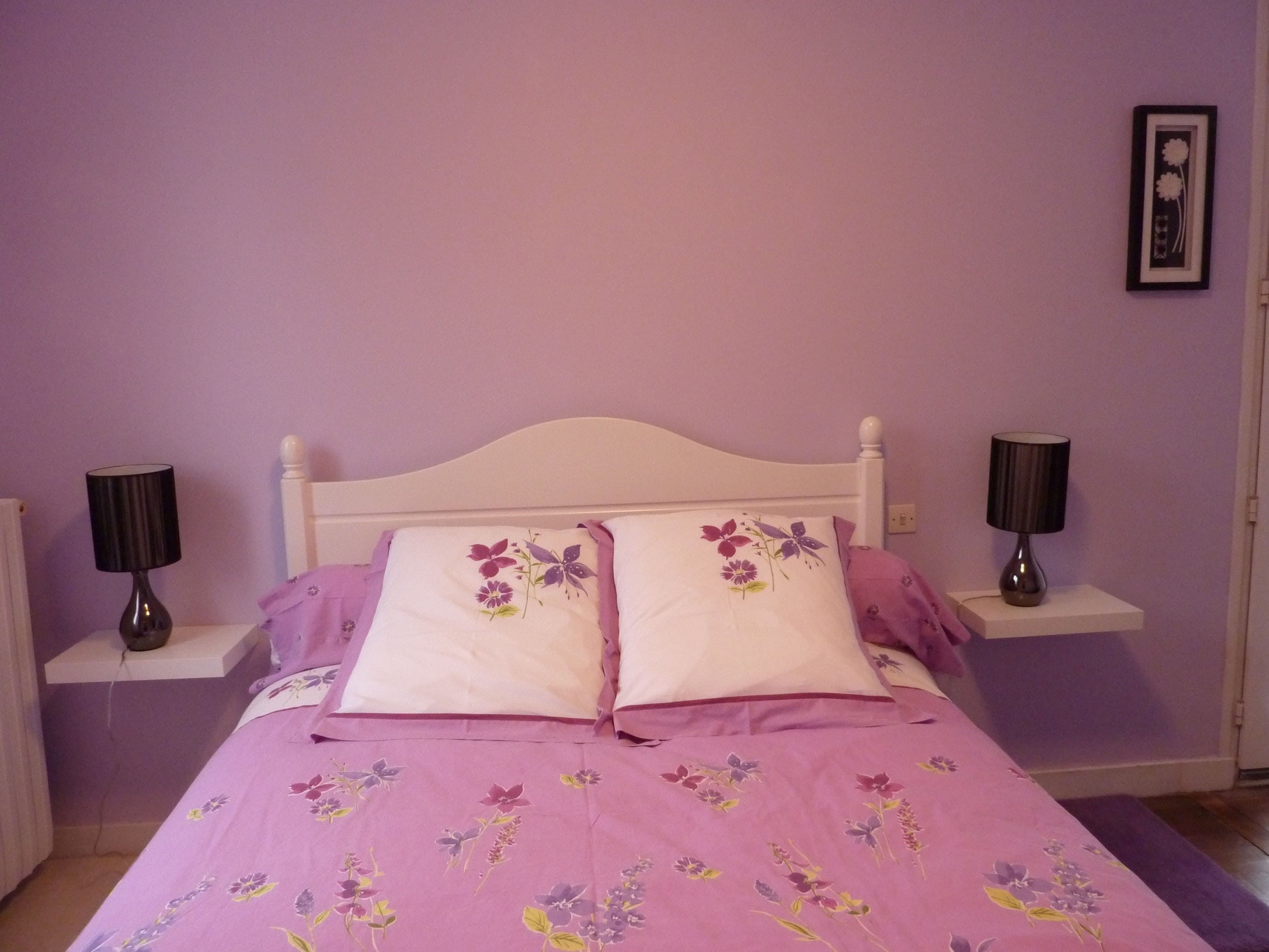 Ein Schlafzimmer mit einem Bett, zwei Nachttischen und einem Wandbild.