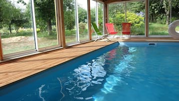 Una piscina techada, sillones reclinables de piscina