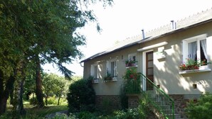A house with a stone foundation, a green staircase, and a garden with various plants and flowers. - Chambres d'Hôtes La Semondière (Saint-Thomas-de-Courceriers)