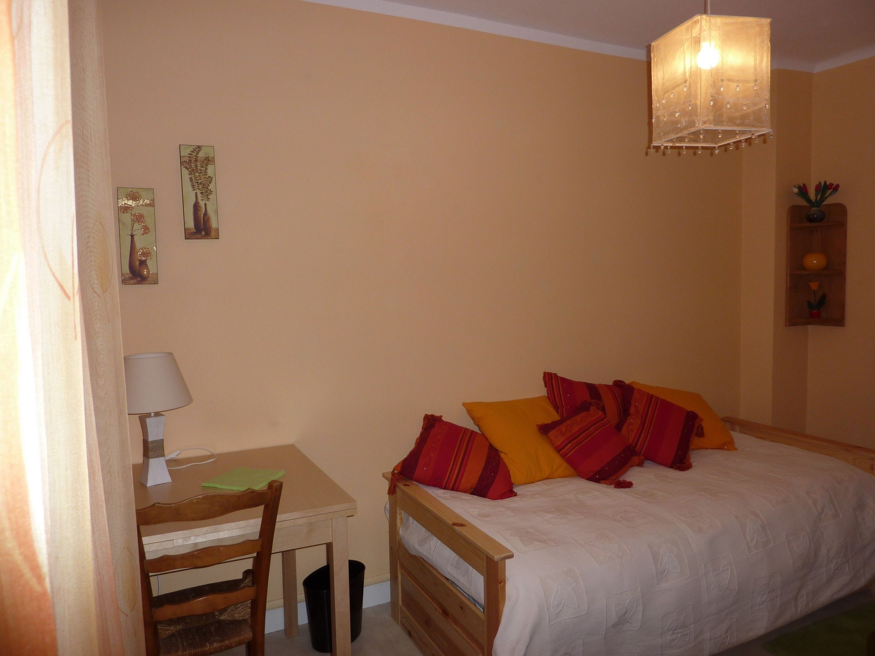 A bedroom with a bed, a desk, and a chair.