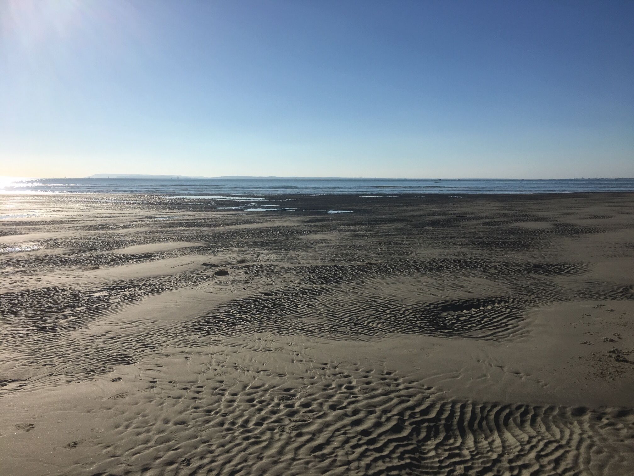 Een strand met duidelijke zandpatronen en een heldere lucht.
