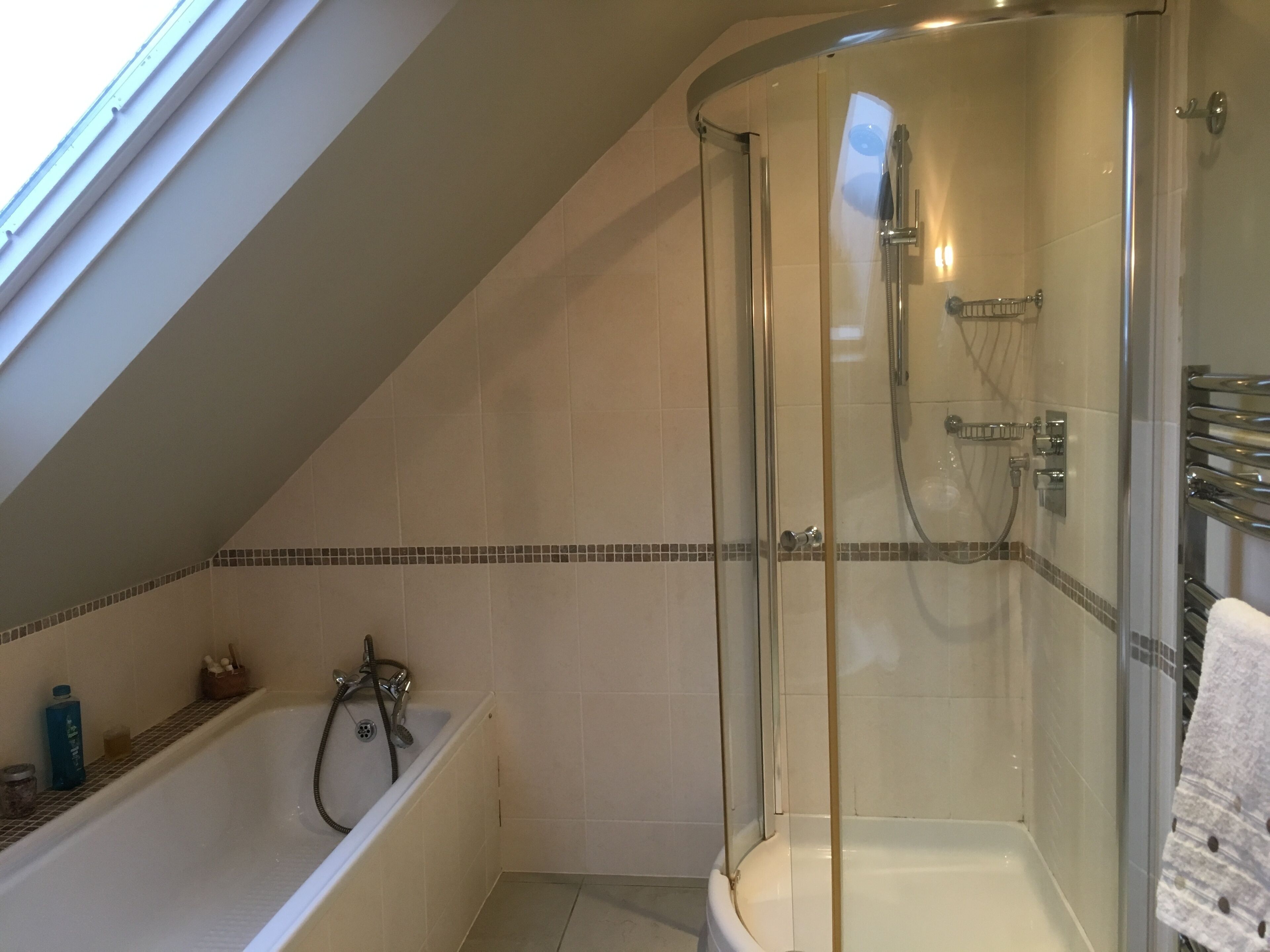 Un baño moderno con ducha acristalada, bañera y zona de ducha con azulejos.