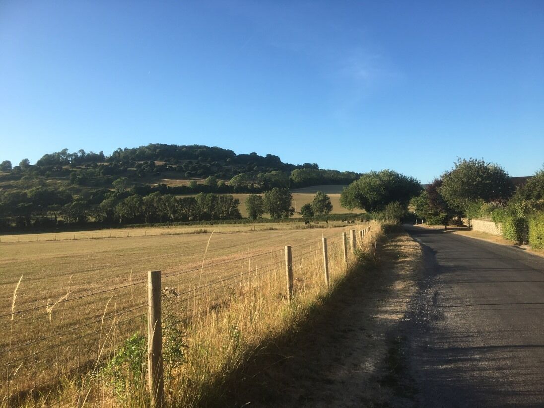 Un camino rural con una cerca a un lado y un campo al otro.