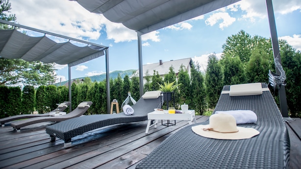 A covered outdoor lounge area with multiple reclining chairs and a table with amenities. - Guest house Oreskovic (Plitvicka Jezera)