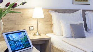 A neatly made bed with white linens and pillows, a bedside lamp, and a tablet displaying a forest scene. - Guest house Oreskovic (Plitvicka Jezera)