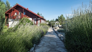 A red cabin with a stone pathway leading to it, surrounded by tall grasses and trees. - Guest house Oreskovic (Plitvicka Jezera)