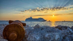 A cruise ship at sunset with rocky foreground and calm sea. - Villa Amor (Rhodes)