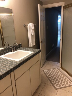 Une salle de bain avec un double lavabo, un porte-serviettes et une porte donnant sur une autre pièce.